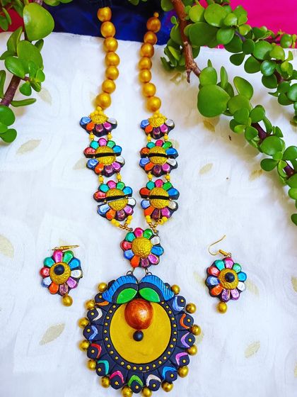 A long, multi-color floral necklace with a large central pendant. This is a statement piece that combines multiple floral elements into one grand design.