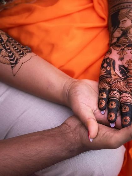 A powerful and intimate shot of the bride and groom's hands, symbolizing their union. The groom's portrait on her arm is a beautiful, personal detail.