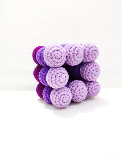 A view of just the crochet bobble pot in shades of purple, showing its unique cube-like structure.