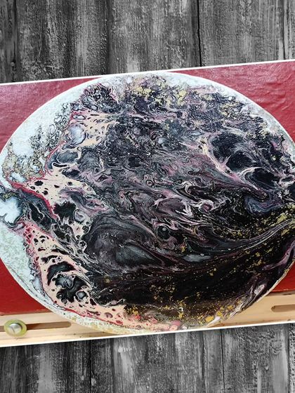 A circular canvas featuring a swirling black, white, and pink fluid art design, showing the versatility of this medium on different shapes.