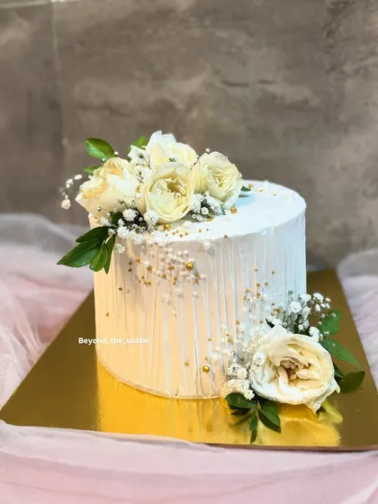 For those who love understated elegance, this minimalist cake is a perfect choice. I created a textured vertical line effect on the white buttercream and adorned it simply with fresh white roses and delicate baby's breath for a timeless look.