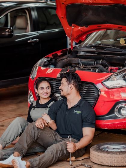 The couple takes a break from 'fixing' the car to share a moment. This shot from the garage-themed session is a great example of finding romance in unexpected places.