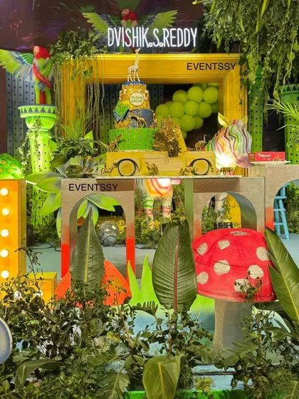 The cake area for the neon jungle party, with a custom-themed cake and a large, illuminated number "1." The entire setup is dense with foliage and animal figures, creating a wild and exciting atmosphere.
