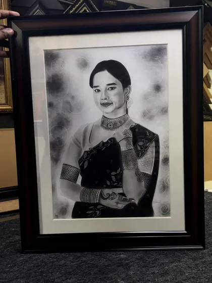 Beyond caricatures, I also create detailed realistic portraits. This framed piece shows the depth and emotion I can capture using charcoal and graphite for a timeless work of art.