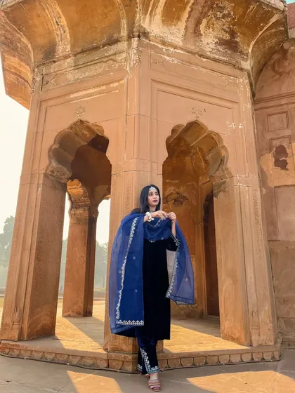 A full-length shot showing the beautiful embroidery on the trousers and the sheer elegance of the organza dupatta. It's a perfect showcase of a complete ethnic look.