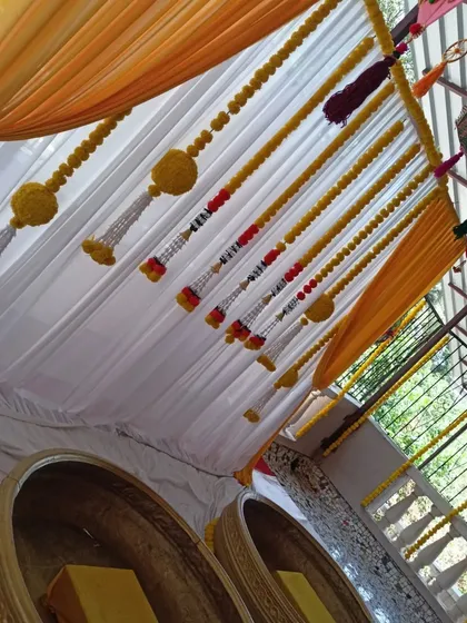A top-down view showing the details of the Haldi decor, including the hanging umbrellas and the marigold strings over the seating area.