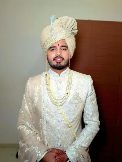 A sophisticated look for a Roka or Tilak ceremony. This groom wears an elegant off-white sherwani, and the makeup is kept natural and polished.