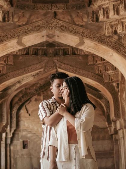 A tender moment captured within the repeating arches of a Delhi monument. The symmetrical composition draws the eye directly to the couple's embrace, creating a powerful and romantic image.