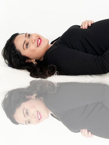 An artistic shot using reflections to create a unique composition. The mother-to-be lies on a reflective surface, creating a dreamy and thought-provoking image.