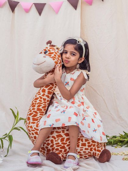 A sweet moment with a favorite toy. She's wearing a comfortable A-line dress with a cute airplane and block print, perfect for imaginative play.