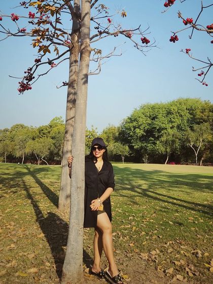 A chic black dress and a cap create a stylish, understated look for a sunny day in the park.