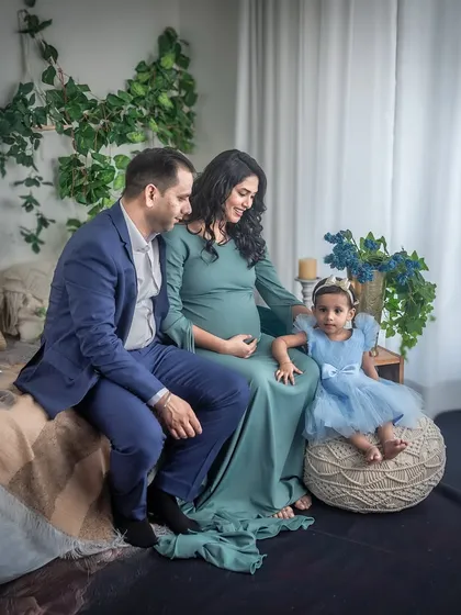 A complete family portrait in the boho studio. The parents and their young daughter are all together, creating a beautiful image of a family excited to welcome a new member.