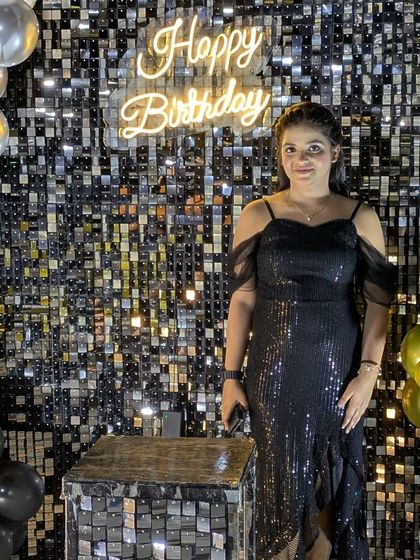 A client posing in front of the black sequin wall, showing how it creates the perfect sparkling background for birthday photos.