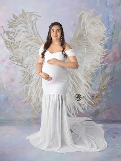 An angelic vision in white. The feather wings add a touch of the divine to this beautiful solo maternity portrait, celebrating the miracle of life.