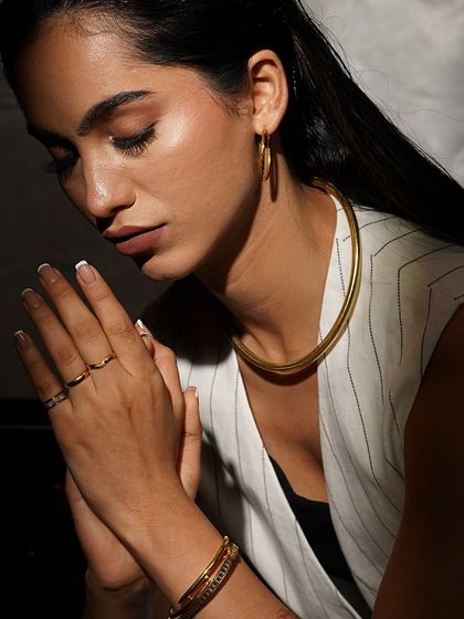 A look of serene confidence, elevated by our Noya gold choker, hoop earrings, and stacked bracelets.