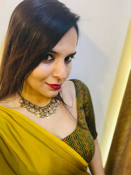 A closer look at the festive saree look. The custom-fit blouse features a green and orange chevron pattern that complements the warm tone of the mustard saree, finished with an antique-style necklace.