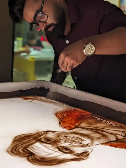 The process of creating the Neeraj Chopra sand art, carefully adding color to his medal.