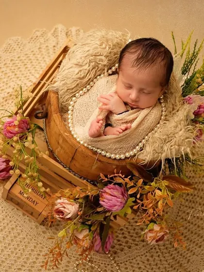 Another angle from our floral newborn session, showcasing the baby resting in a wooden crate prop. We use pearls and vintage-style elements to add a classic, elegant touch.