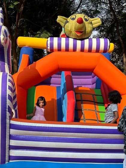 Kids enjoying the inflatable bouncy castle at the outdoor butterfly-themed party.