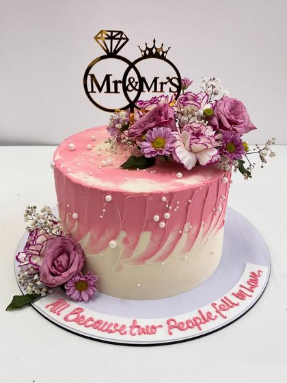 A still shot of our romantic pink and white floral anniversary cake. The combination of textured buttercream, fresh flowers, and a "Mr & Mrs" topper makes it perfect for celebrating love.