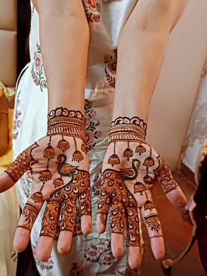 This design features peacocks and hanging jhumkas, creating a beautiful and festive look on the palms without being too dense.