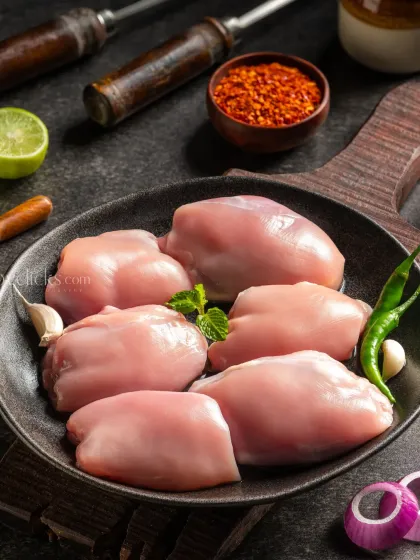 Raw boneless chicken thighs in a cast-iron pan, shot with moody lighting to create a rustic and dramatic look.