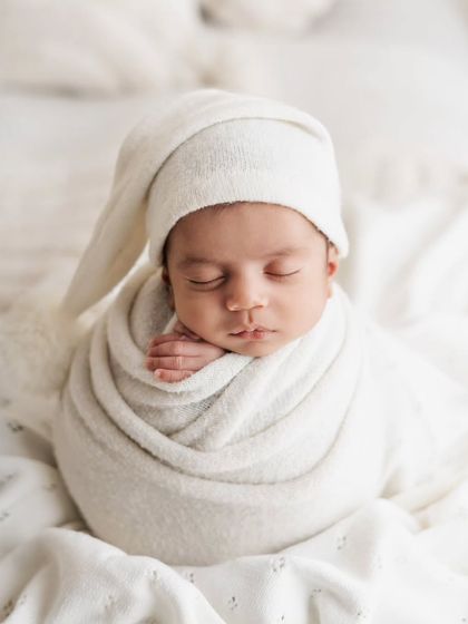 Another angle of this peaceful baby in an all-white setup. The soft lighting and textures create a dreamy, angelic feel for this classic newborn photo.