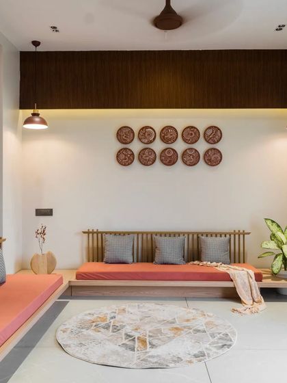 The living space in 'Yashodanand' features low, informal seating and wall art made of traditional painted plates, creating a relaxed and culturally rich atmosphere.