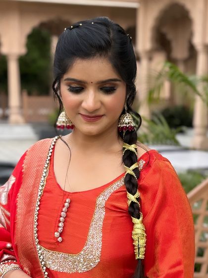 A beautiful traditional look with a modern twist. The makeup features a bold smokey eye with a pop of glitter, paired with an intricate braid hairstyle.