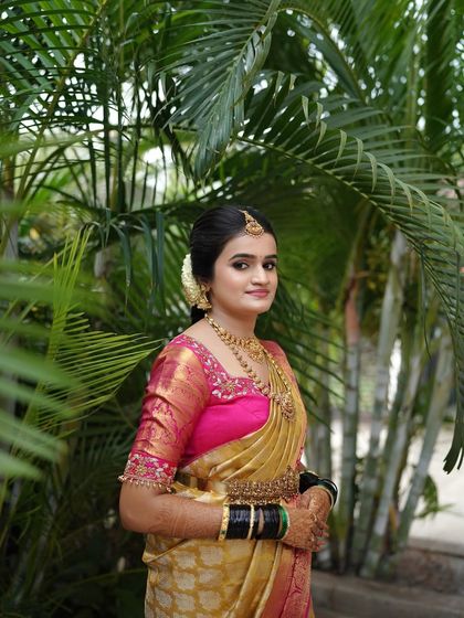 This bride looks stunning against the lush green background. The colors of her saree pop, and her radiant makeup gives her a fresh and youthful glow.