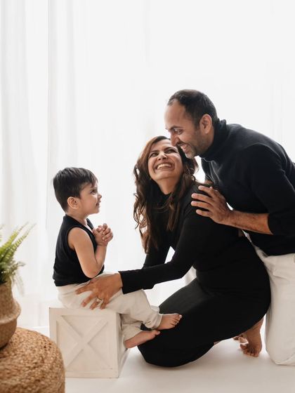 A candid and interactive family portrait in the studio. The parents are fully engaged with their son, creating a natural and loving scene.