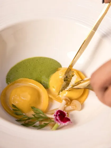 A delicate moment with our Truffle Fungi Cream Cheese Ravioli, part of the Holiday Feast. The filling is revealed, showcasing the rich, creamy texture inside.