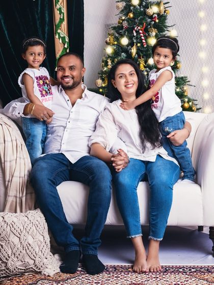 A happy family of four in matching white tops and jeans. This classic, casual look works beautifully with the festive Christmas background.