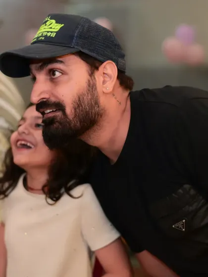 A father and daughter sharing a laugh while watching the party entertainment.