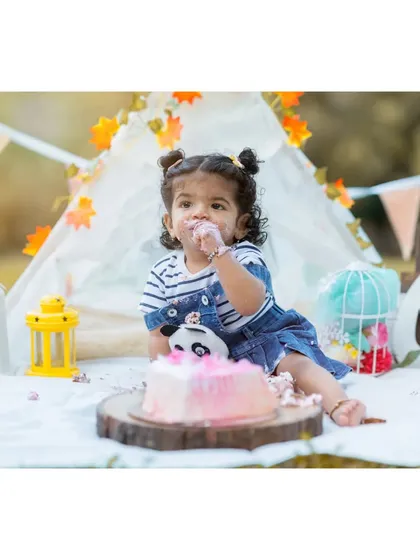 A wider view of Nitya's cake smash setup. This shows how all the elements, from the props to the outfit, come together to create a cohesive and beautiful theme for a first birthday photoshoot.