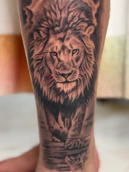 A slightly different angle of the lion tattoo, showing the contrast between the dark background and the illuminated face.
