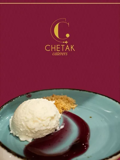 A scoop of white, creamy dessert served with a rich berry reduction and a sprinkle of crumble. The contrast of colours on the blue plate makes this dish visually striking.