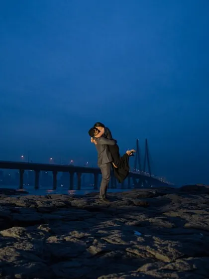 A powerful and romantic lift against the dramatic twilight sky and the Bandra-Worli Sea Link, showcasing a cinematic approach to urban pre-wedding photography.