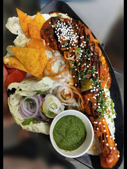 A creative presentation of our Mutton Pahadi Bawra. The dish is served with cheese sauce pasta and nachos, offering a unique fusion of flavors and textures.