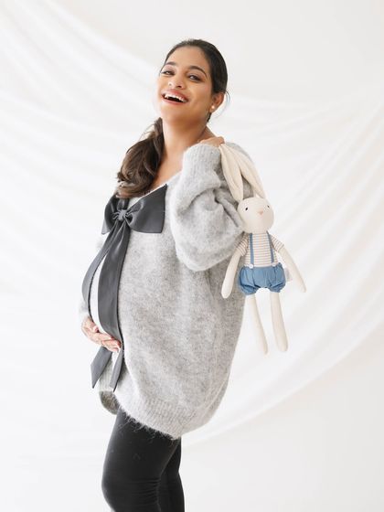 A joyful portrait of the mother-to-be holding a cute stuffed bunny, hinting at the nursery and the sweet moments to come.