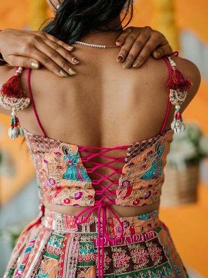 For Chethana's mehendi ceremony, I created this vibrant and playful lehenga. The skirt features colorful patchwork embroidery, and the blouse is designed with a modern tie-up back and charming tassels.