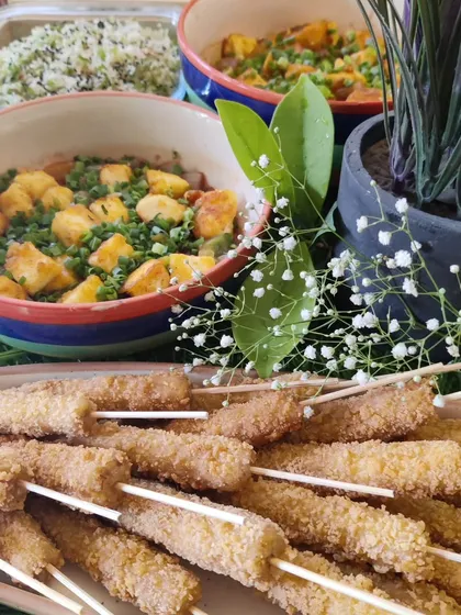 A snapshot of a catered meal featuring some of our Asian specialties. In the foreground, you can see our crispy baby corn skewers, with bowls of fried rice and a tofu main course in the background.