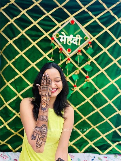 My gorgeous bride Pooja, smiling and hiding her face behind her mehendi.