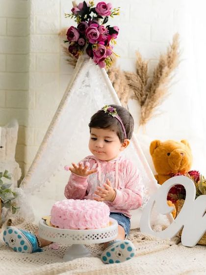 A sweet and messy moment from a first birthday celebration. This little girl is enjoying her pink cake in a lovely bohemian-themed setting.