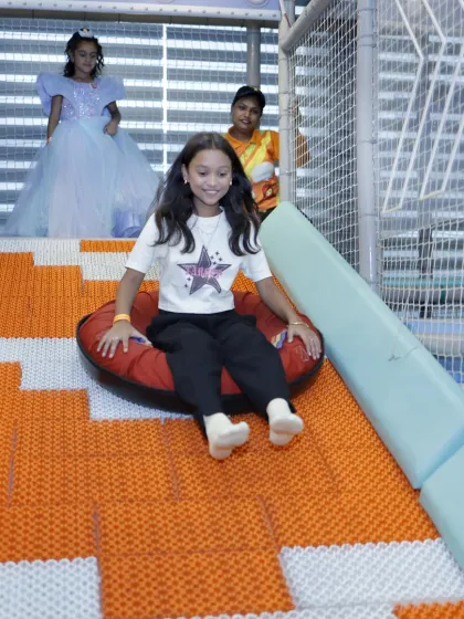 The doughnut slide offers a unique sliding experience. Here, a girl glides down on an inflatable tube, with our staff member watching closely from the top.