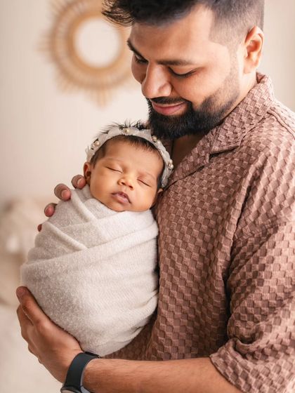 A proud father holds his sleeping daughter close. These individual parent-and-baby portraits are a wonderful way to document that special, one-on-one bond.
