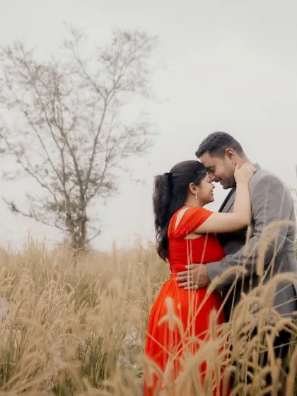 An intimate portrait of a couple touching foreheads in a field, capturing a moment of deep connection.