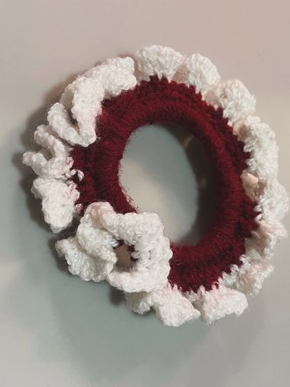 A close-up of a red and white ruffled crochet hairtie, perfect for a simple bun or ponytail.