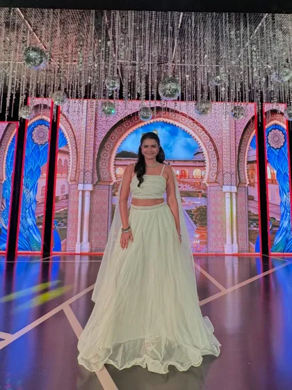 A full view of my white lehenga against the grand LED screen, which displayed a beautiful palace arch, enhancing the royal theme of the Sangeet.
