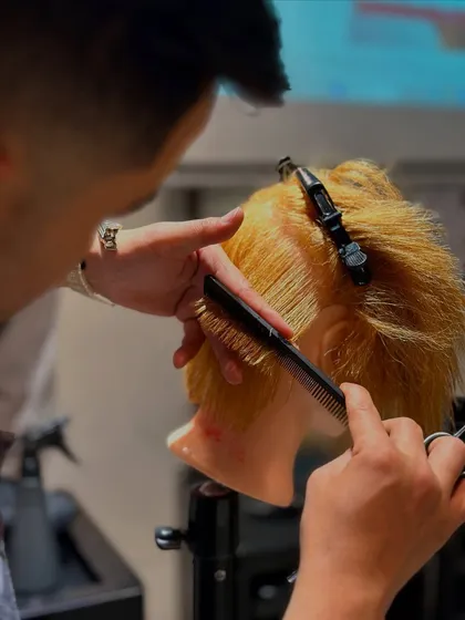 This shot captures the intricate detail involved in a precision bob cut. Our students learn to master control over the comb and scissors for flawless results.